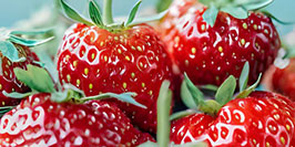 Close-up of ripe strawberries with vibrant red color and fresh green leaves.